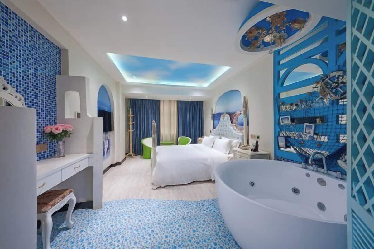 Une chambre d’hôtel moderne dotée d’une grande baignoire, d’un lit, d’une coiffeuse et d’un coin salon.