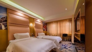 Une chambre d’hôtel avec deux lits, un bureau, une chaise et une grande fenêtre avec des rideaux.