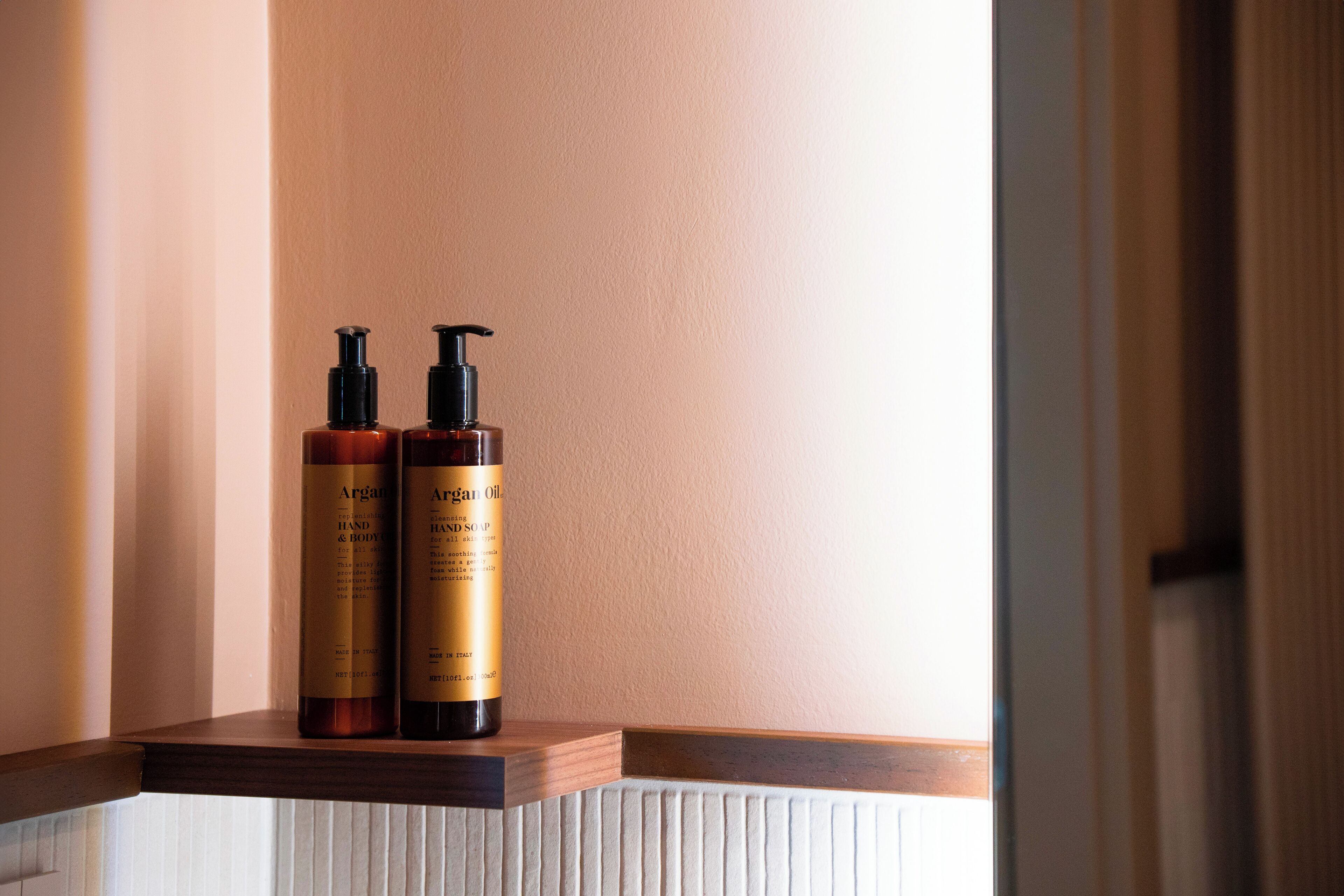 Two bottles of Argan Oil on a wooden ledge.