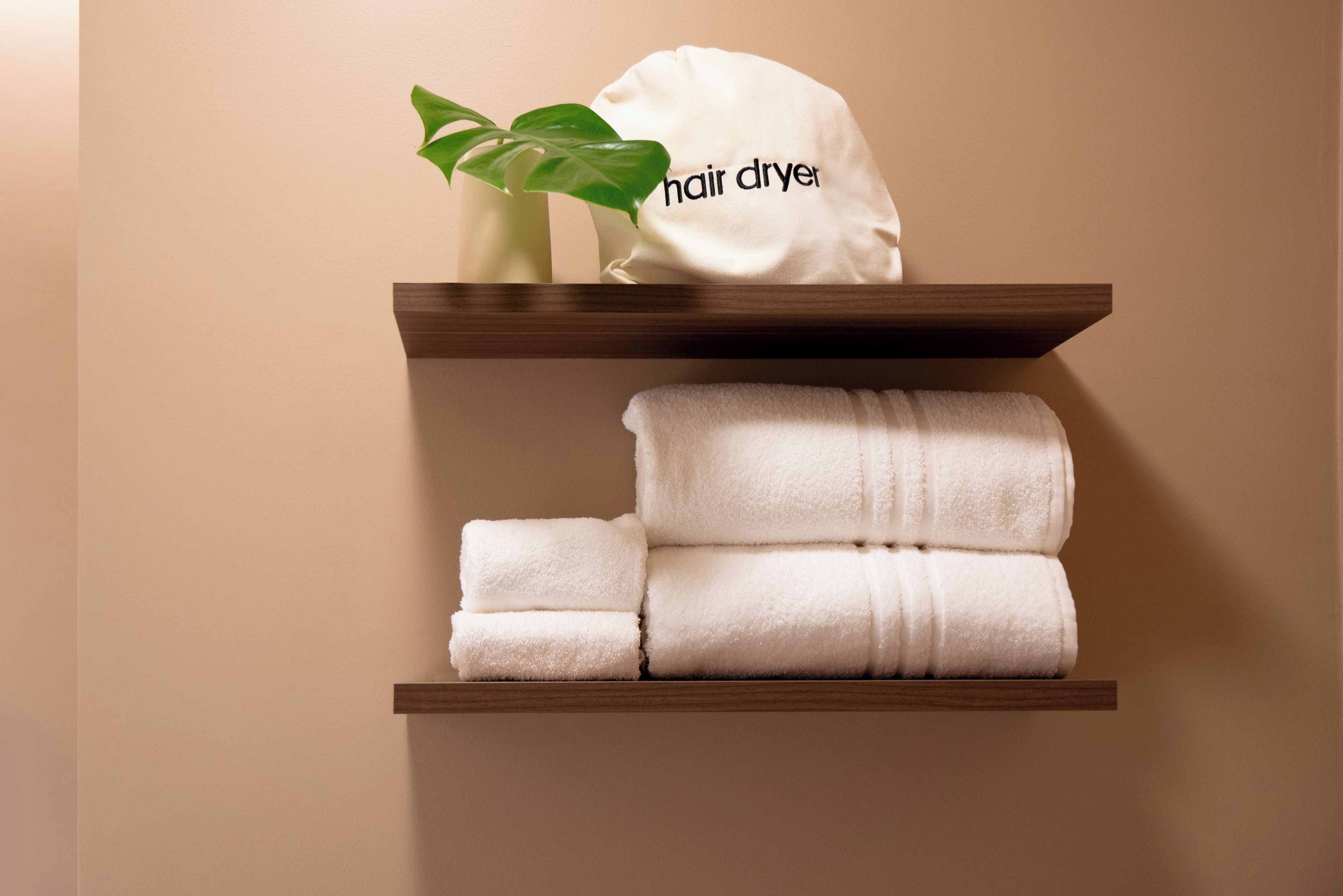 A shelf with a hair dryer and folded towels.