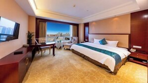 A hotel room with a large bed, a desk, a chair, a TV, and a view of the cityscape. - Huatian Hotel(Wuhan Xudong Metro Station) (Wuhan)