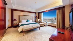 A hotel room with a large bed, a desk, a chair, a TV, and a window with a city view. - Huatian Hotel(Wuhan Xudong Metro Station) (Wuhan)