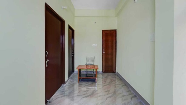 A hallway with a marble floor, wooden doors, and a small table with chairs. - Hotel Kashyap By GRB (Patna)