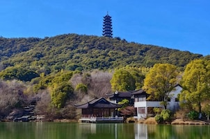 Uma pagoda tradicional numa colina, com um lago e edifícios ao primeiro plano.