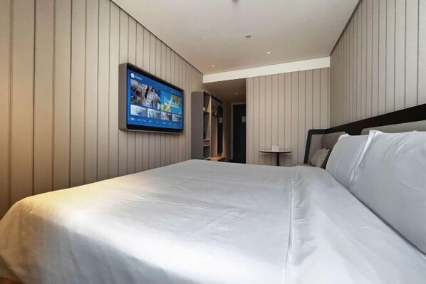 A modern hotel room with a large bed, a flat-screen TV mounted on the wall, and a minimalist design. - HanTing Hotel (Zhangjiagang Jingang RT-MART Branch) (Zhangjiagang)