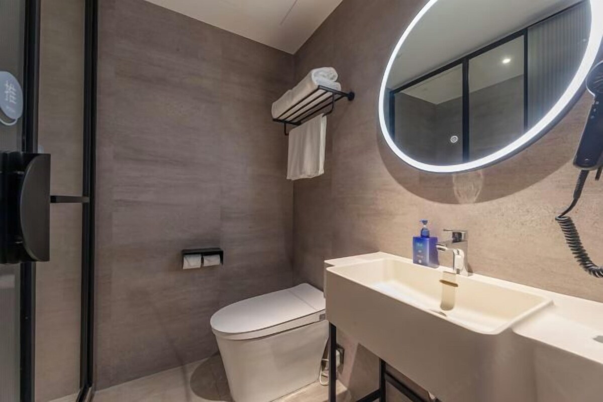 A modern bathroom with a toilet, a sink with a mirror, and a towel rack.