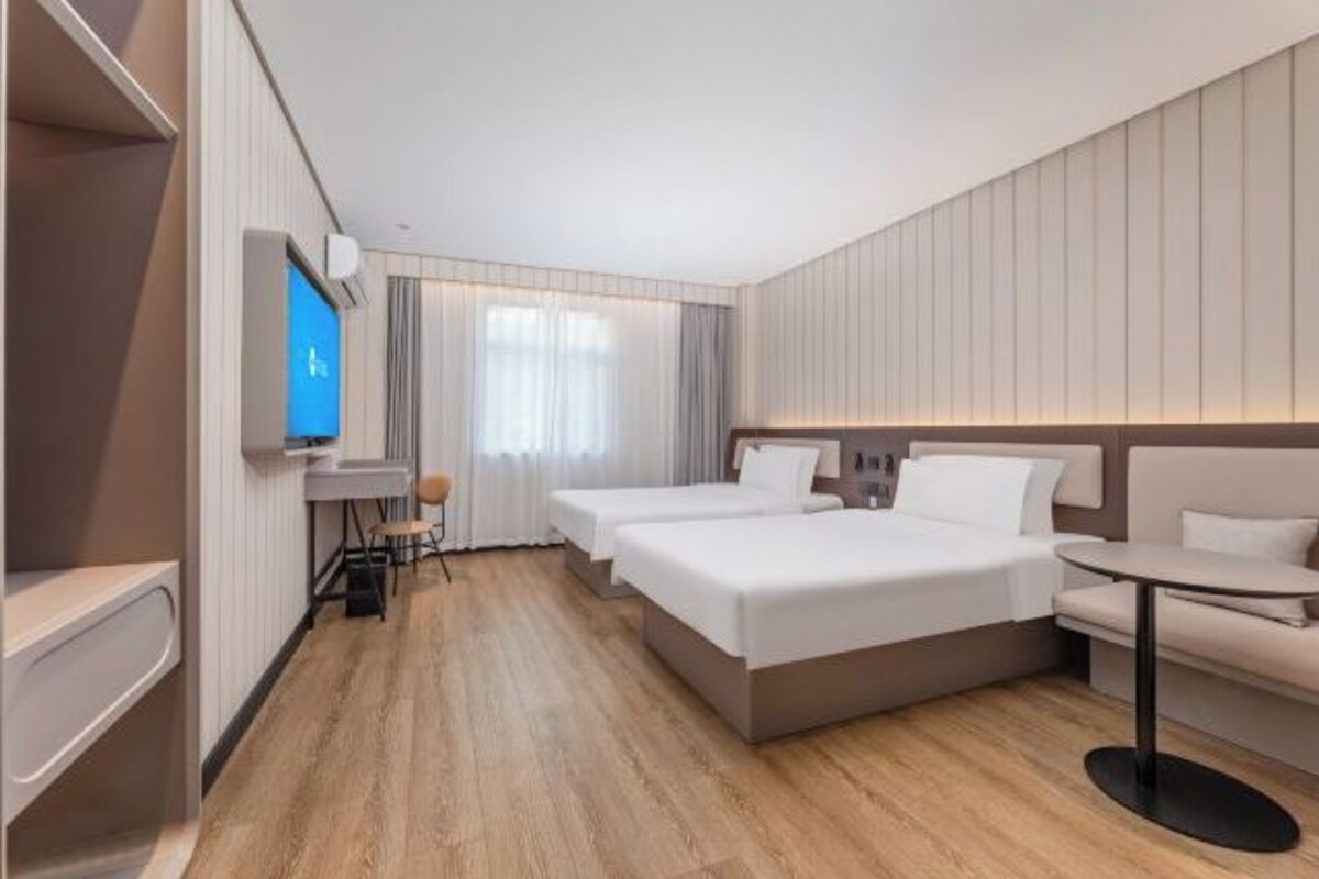 Ein Hotelzimmer mit Bett, Nachttisch, Stuhl und Fernseher.