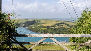 Une vue sur la côte, avec une clôture en bois, de la végétation et des bateaux sur l’eau.