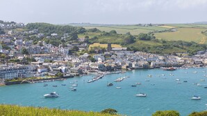 Une ville côtière dotée d’un port où sont amarrés de nombreux bateaux, entourée de bâtiments résidentiels et de collines verdoyantes.