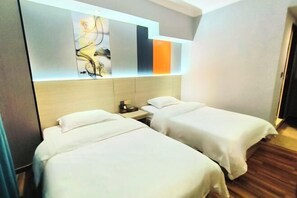 Une chambre d’hôtel avec deux lits, une table de chevet et une œuvre d’art moderne accrochée au mur au-dessus des lits.