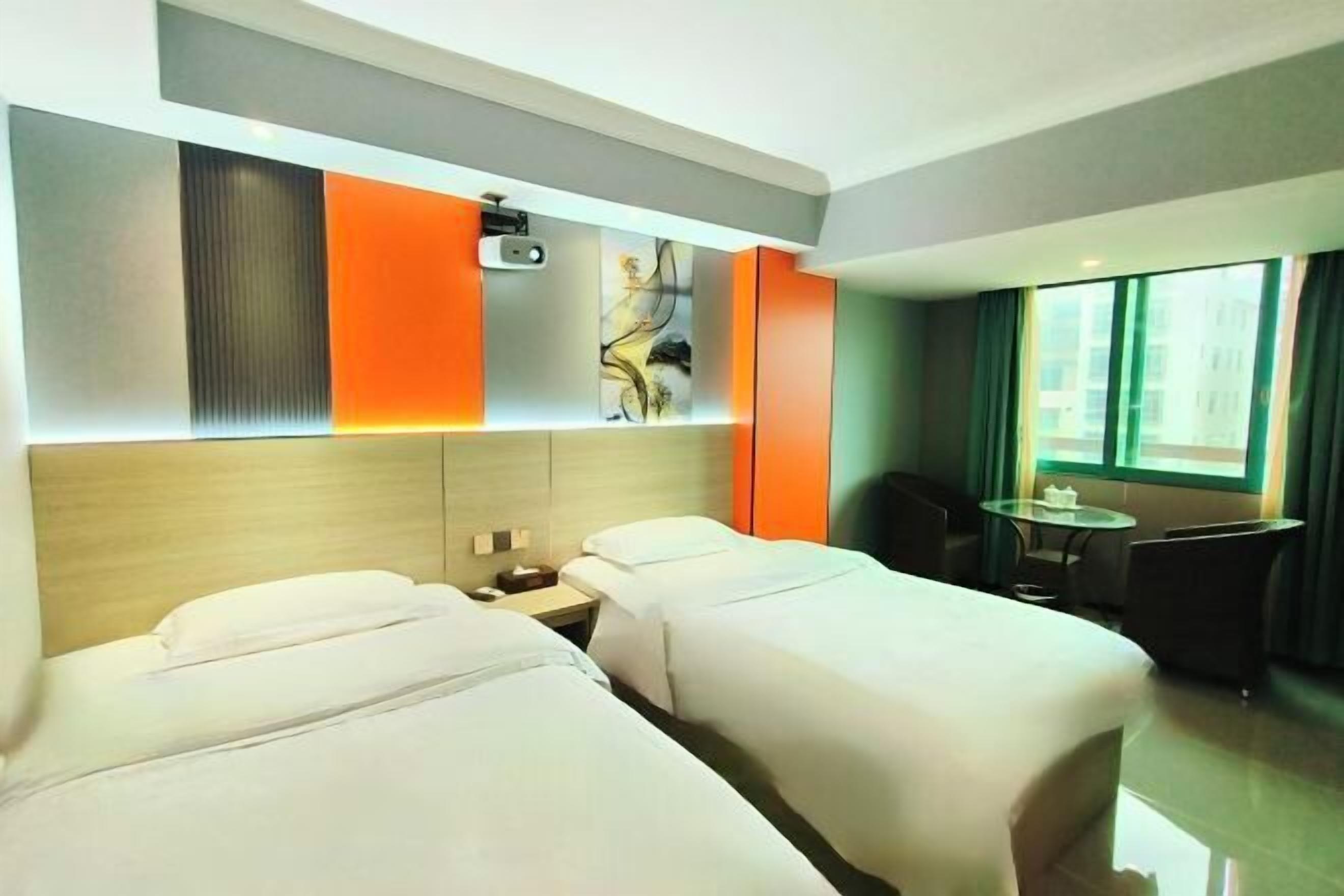 Een hotelkamer met twee bedden, een bureau, een stoel en een groot raam.