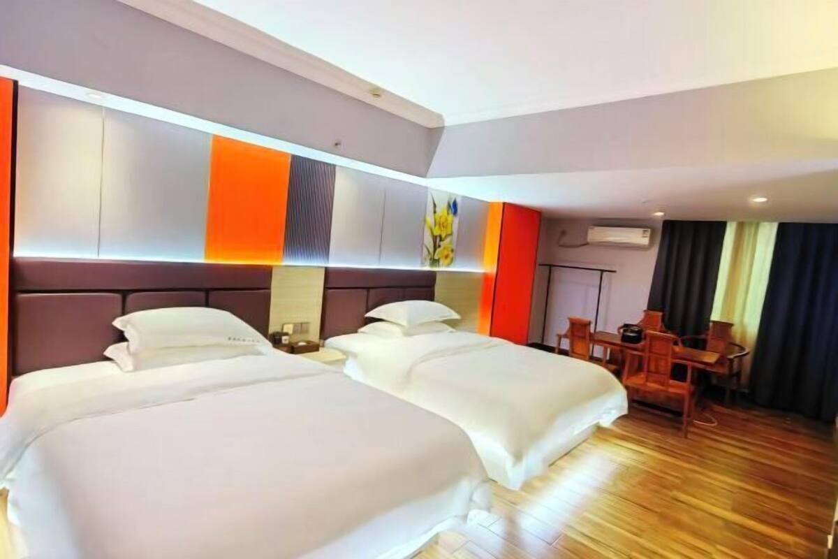 A hotel room with two beds, a desk, and a chair.