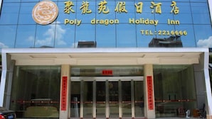 Ett hotell med en fasad av glas och en skylt med texten ”Poly dragon Holiday Inn” samt ett telefonnummer.
