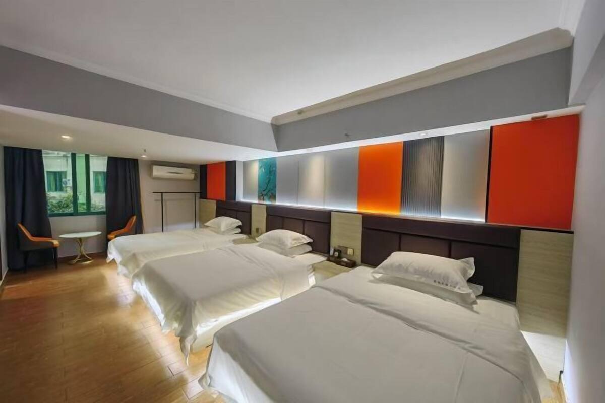 A hotel room with three beds, a small table, and a chair.