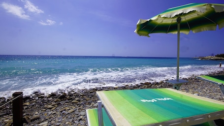 Playa privada, arena negra, sillas reclinables de playa, sombrillas