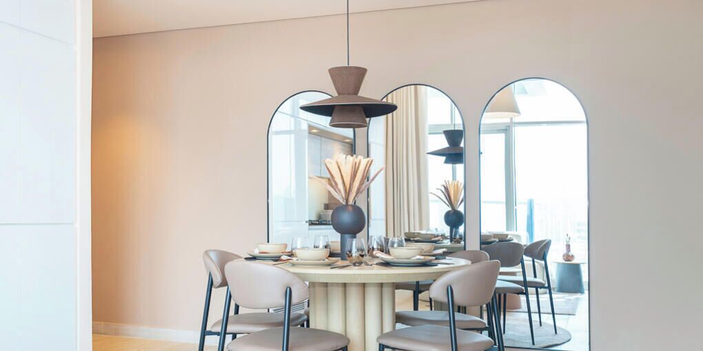 A dining area with a round table, chairs, and a pendant light.