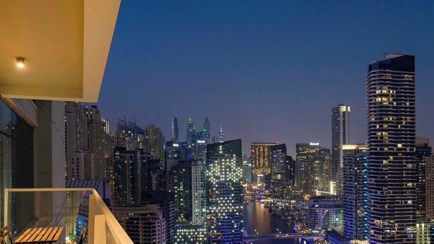 A cityscape at night with illuminated buildings and a river. - LUX The Ultimate Marina View Suite (Dubai)