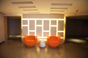 Een kamer met twee oranje stoelen, een kleine tafel en een wand met verlichte panelen.