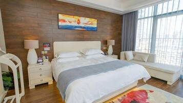 Ein modernes Hotelzimmer mit einem großen Bett, Nachttischen, einer Sitzecke und Blick durch große Fenster.