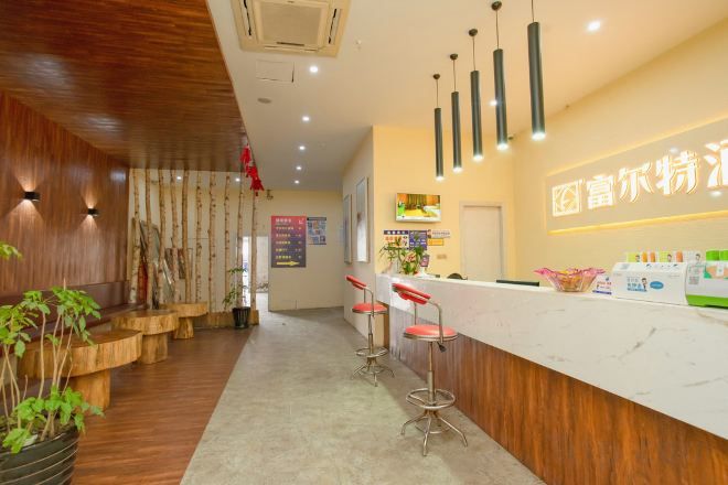 A reception area with a wooden interior, a white reception desk, and a seating area with stools.