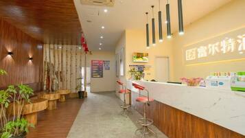 A reception area with a wooden interior, a white reception desk, and a seating area with stools.