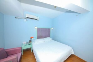 Un dormitorio con cama, mesita de noche, silla y equipo de aire acondicionado.