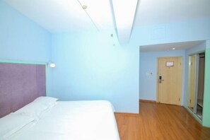 Ein Hotelzimmer mit einem Bett, Holzboden und einer Tür zu einem anderen Raum.