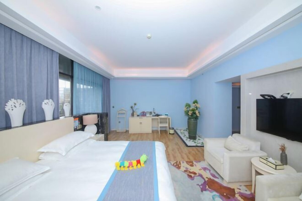 Una habitación de hotel moderna con una cama grande, un escritorio y un televisor.