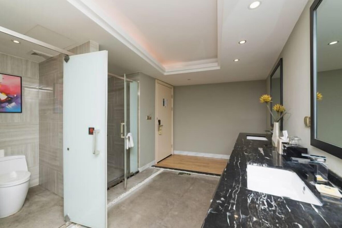 Un baño moderno con tocador de mármol, un espejo grande y zona de ducha.