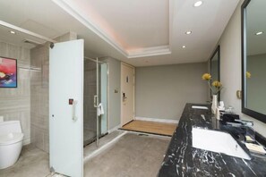Un baño moderno con tocador de mármol, un espejo grande y zona de ducha.