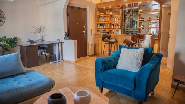Ein Wohnzimmer mit einem blauen Sofa, einem Holztisch und einem Essbereich mit einer Bar.