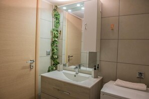 A modern bathroom with a wooden vanity, a sink, a mirror, and a toilet. - Urban Oasis Stylish Apt in Piraeus Centr (Piraeus)