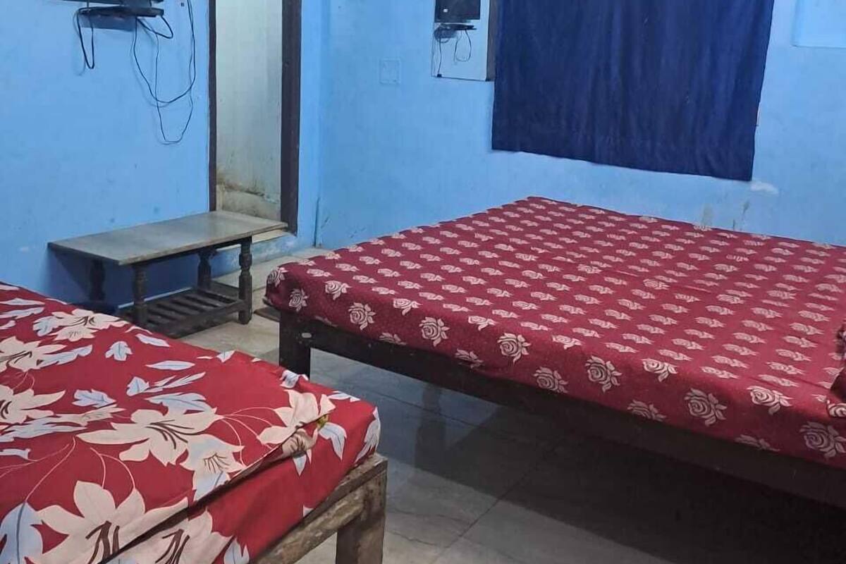 A room with two beds, a television, and a window with a curtain.