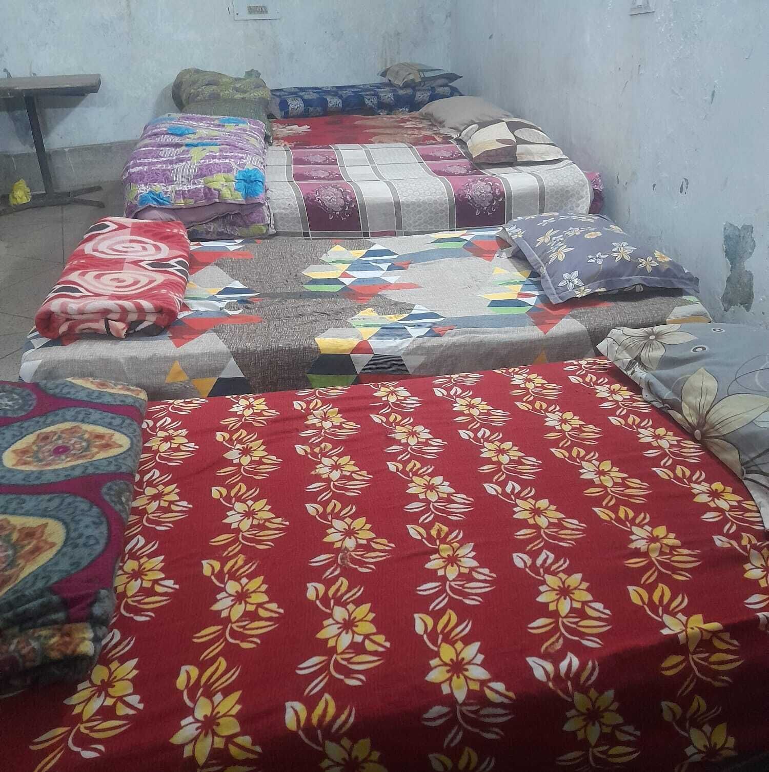 Een kamer met twee bedden, elk voorzien van een ander beddegoed met verschillende patronen.