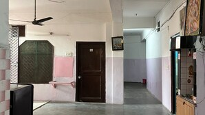 A hallway with a ceiling fan, a door, and a wall-mounted light fixture. - Bhaskar Hotel By GRB (Ghaziabad)