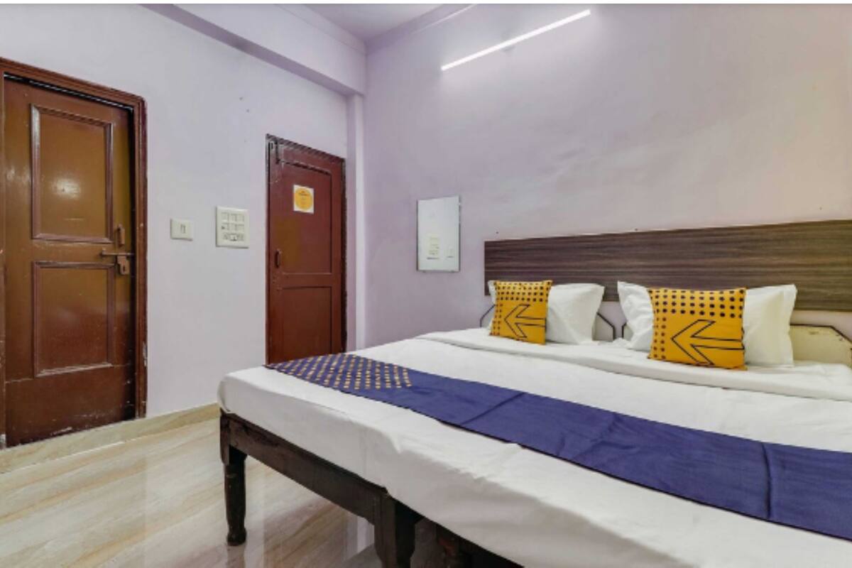 A hotel room with a bed, wooden doors, and a light switch on the wall.