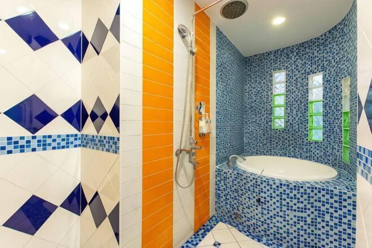 A bathroom with a bathtub, shower, and tiled walls.