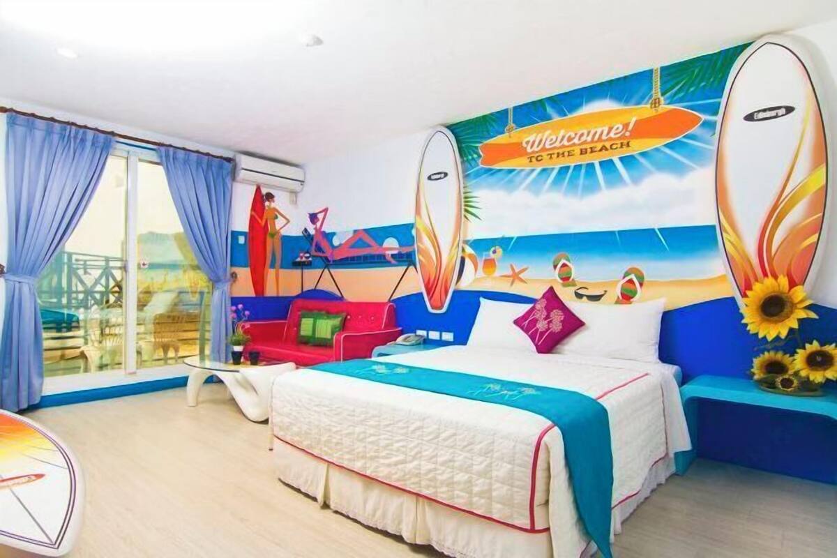 A bedroom with a bed, a sofa, a window with curtains, and a wall mural.