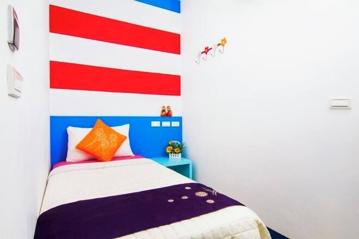 A bed with a blue headboard, a white pillow, and a purple blanket.