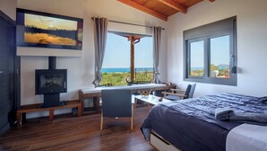 A bedroom with a bed, a desk with a chair, a TV, and a window with a view of the sea. - Cozy Retreat - Discover tranquility in Maleme, Crete. (GV82+HP2 Maleme, Greece)