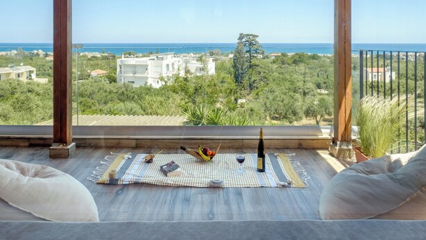 A balcony with a view of the sea, a bottle of wine, a bowl of fruit, and a book on a checkered mat. - Cozy Retreat - Discover tranquility in Maleme, Crete. (GV82+HP2 Maleme, Greece)