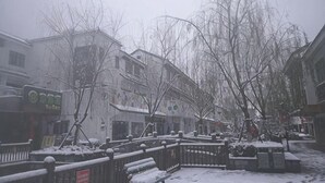 A snow-covered street with buildings, benches, and a fence. - Yiwenge Hotel (Changshu)