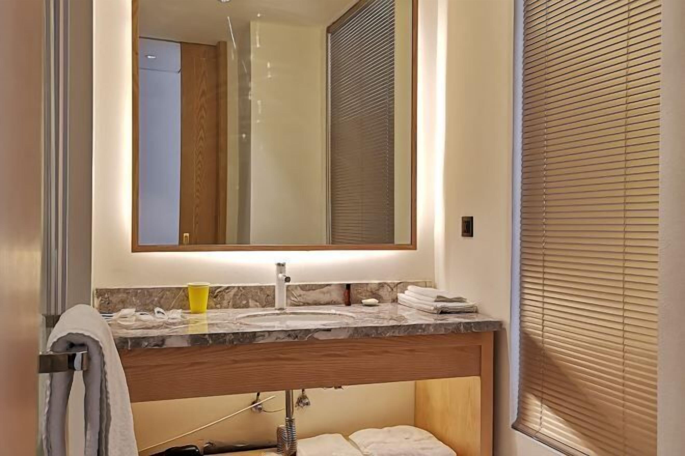 A bathroom with a marble sink, a mirror, and a towel rack.