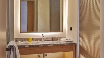 A bathroom with a marble sink, a mirror, and a towel rack.