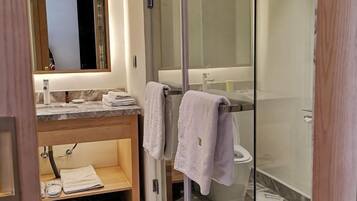 A modern bathroom with a glass shower enclosure, a marble countertop, and a wooden vanity.