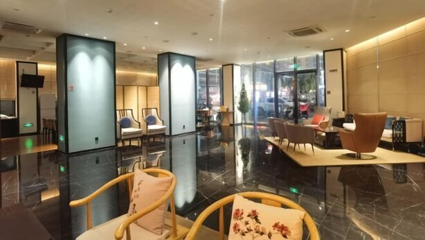 A modern hotel lobby with a polished floor, seating areas, and large windows offering a view of the city. - Yiwenge Hotel (Changshu)