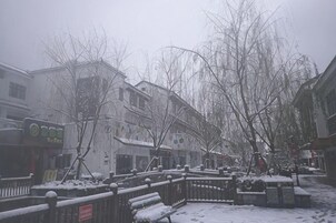 Una calle cubierta de nieve con edificios, bancos y una valla.