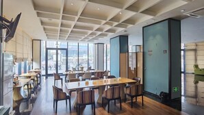 A spacious dining area with high ceilings and large windows offering a city view. - Yiwenge Hotel (Changshu)