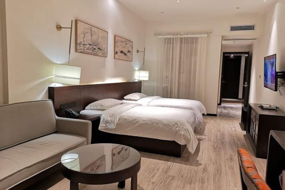 A hotel room with a bed, a sofa, a small table, and a TV.