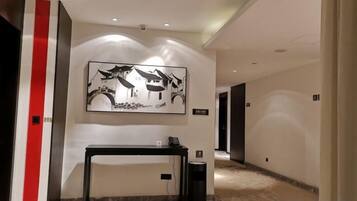 A hallway with a reception desk, a framed artwork, and a trash bin.